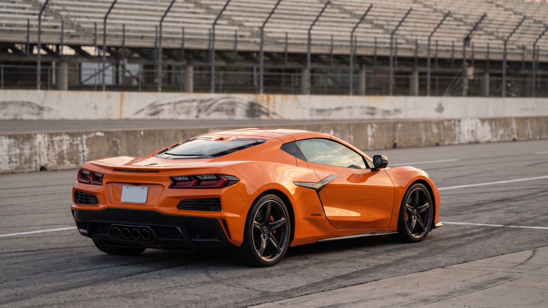 Orange Chevrolet Corvette Z06 in a race track pit lane, seen from the rear