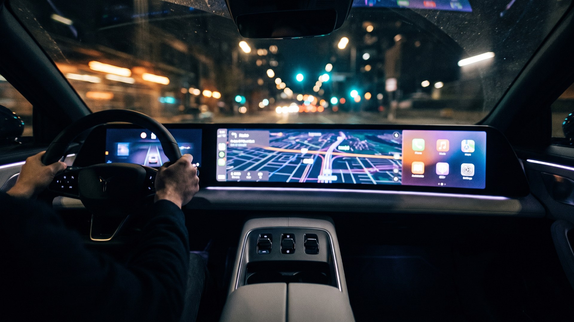Driver at night in a cabin dominated by a wide dashboard touchscreen showing navigation and app icons