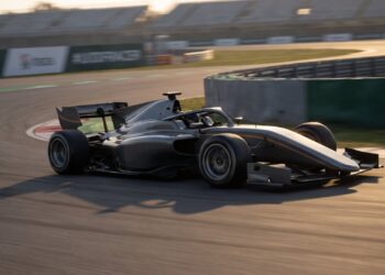 Dark grey open-wheel single-seater with halo cornering on a circuit at sunset