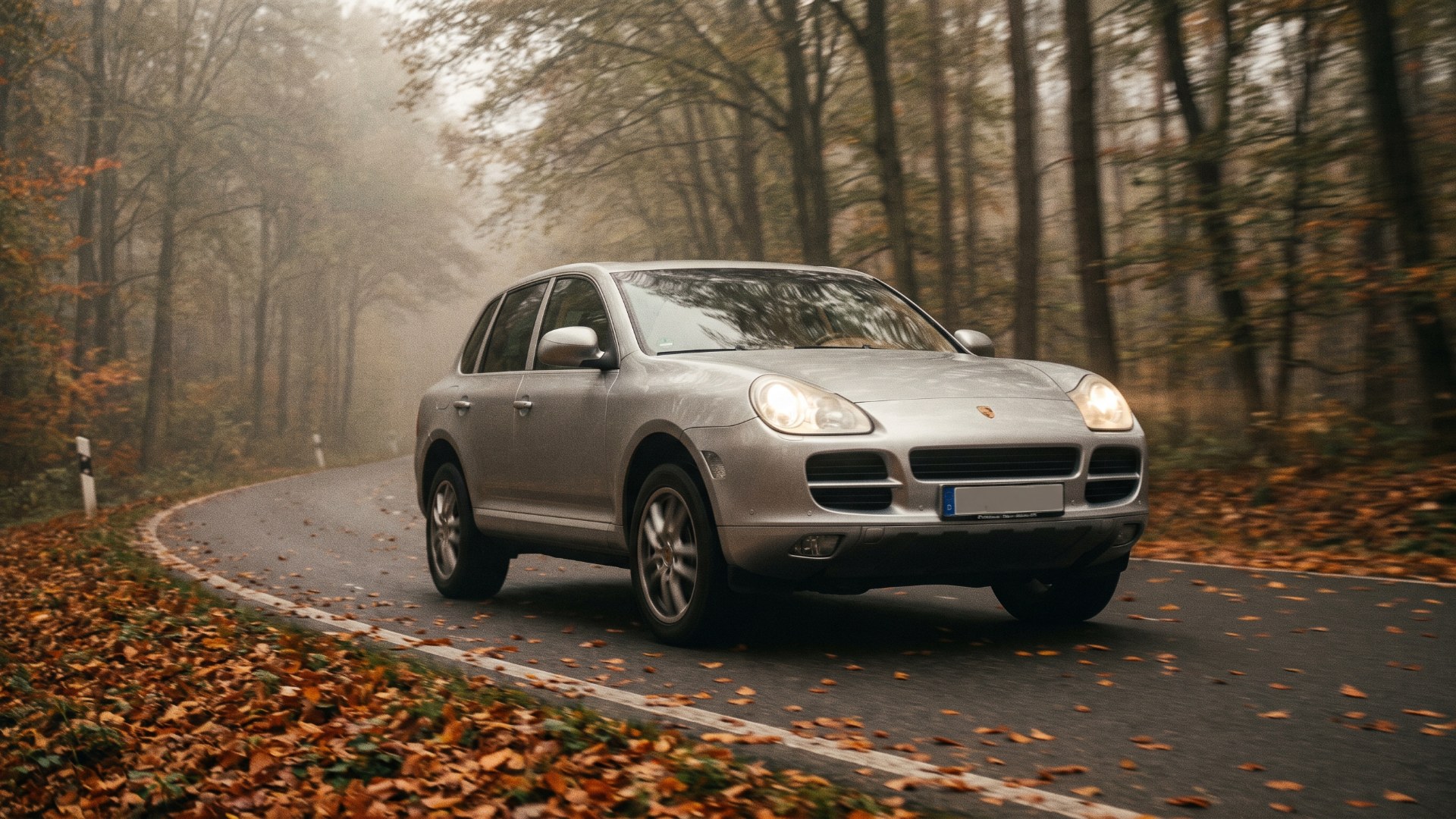 First-generation Porsche Cayenne on a forest road in autumn