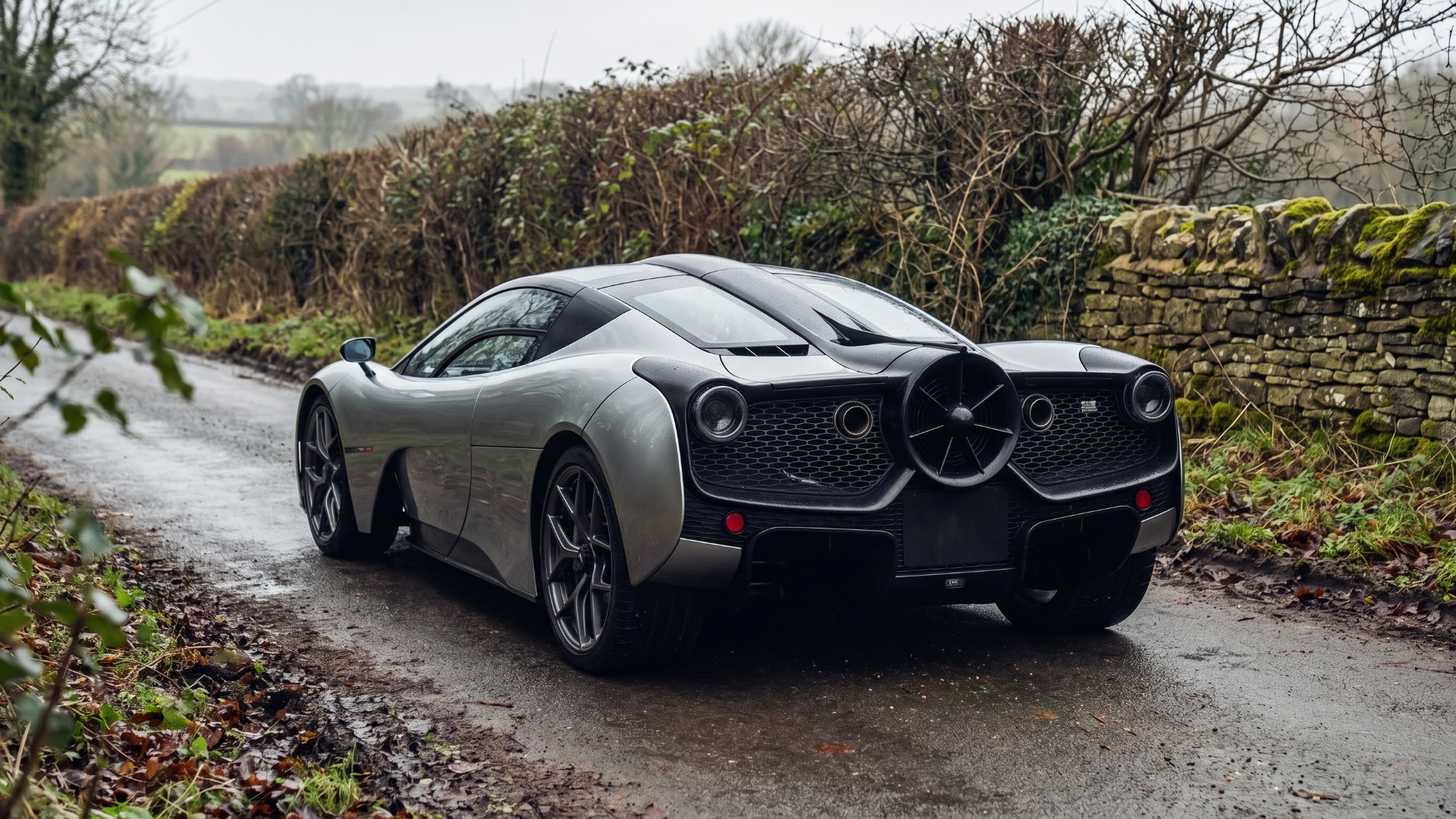Silver Gordon Murray Automotive T.50 on a country lane, showing the large fan at the center of its tail