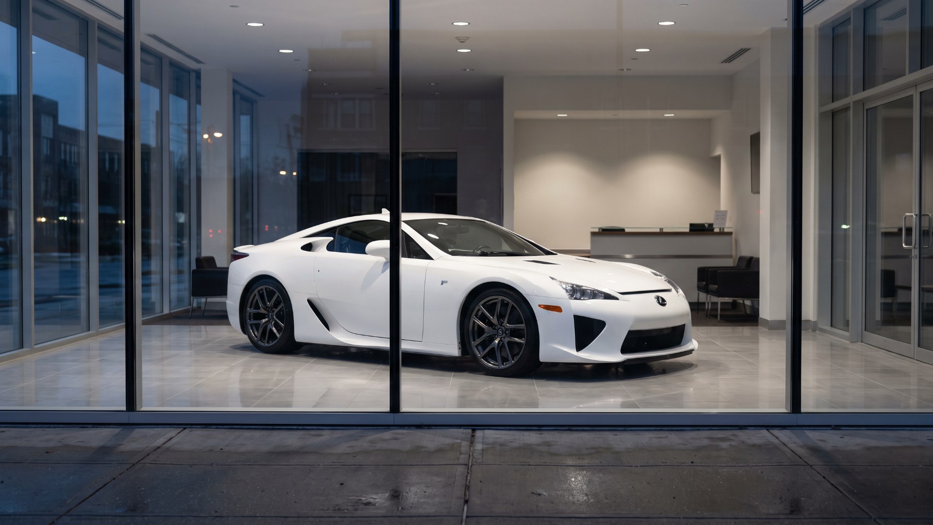 White Lexus LFA seen through the glass of a dealership showroom at dusk