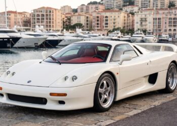 Ivory-white MCA Centenaire supercar parked on a harbor quay in Monaco