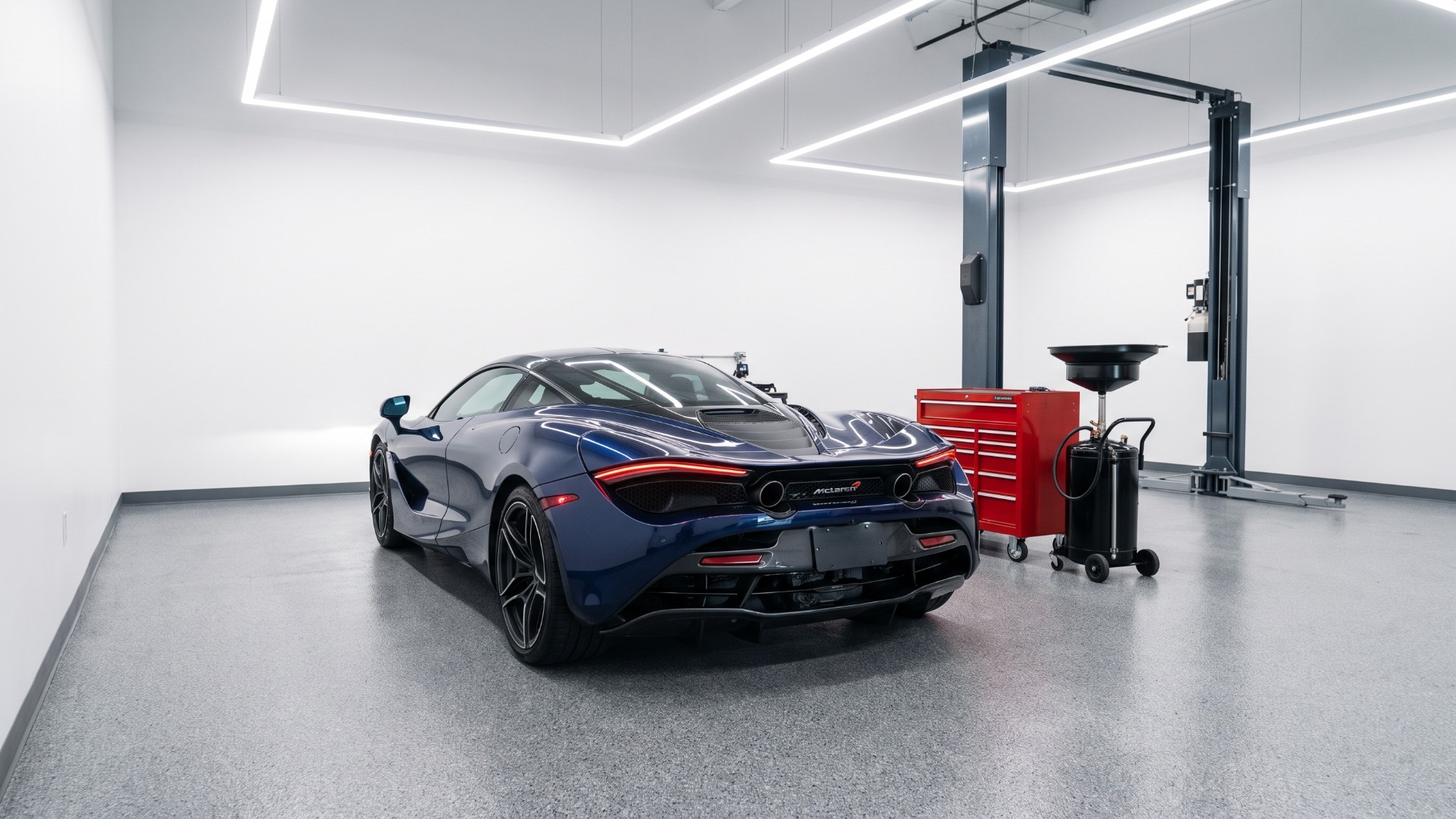 Blue McLaren 720S coupe seen from the rear in a service workshop beside a tool chest