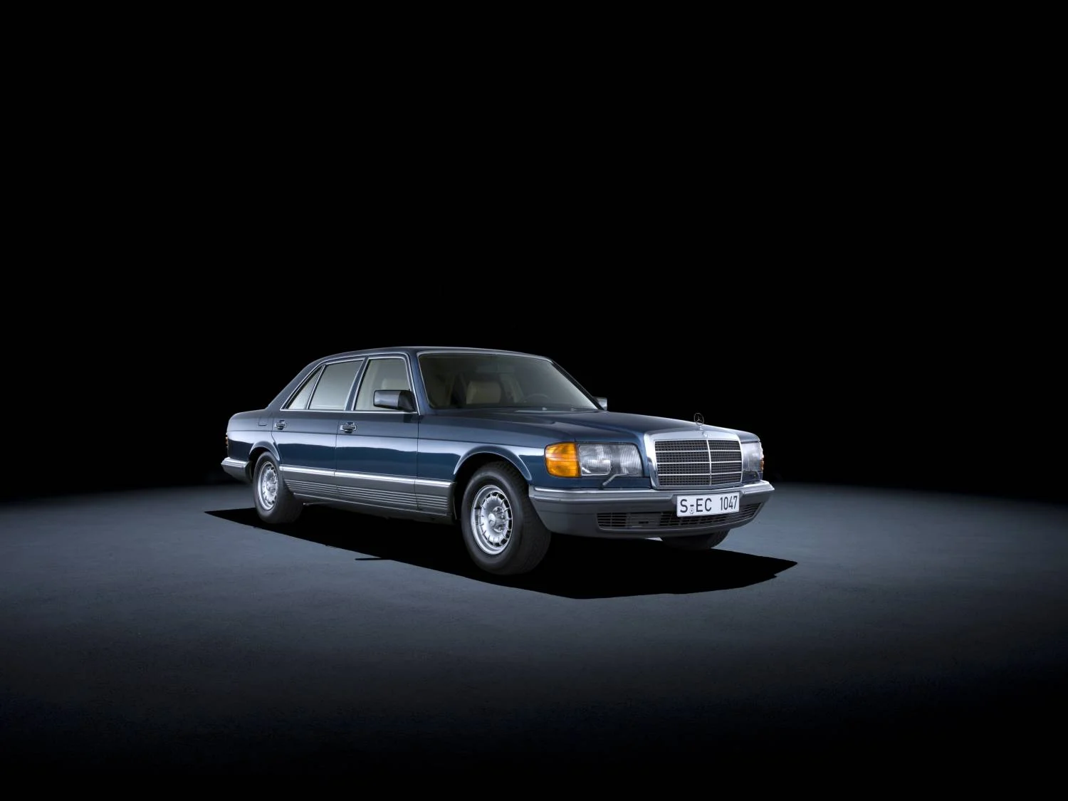Dark blue Mercedes-Benz 500 SEL W126 sedan in a studio, front three-quarter view