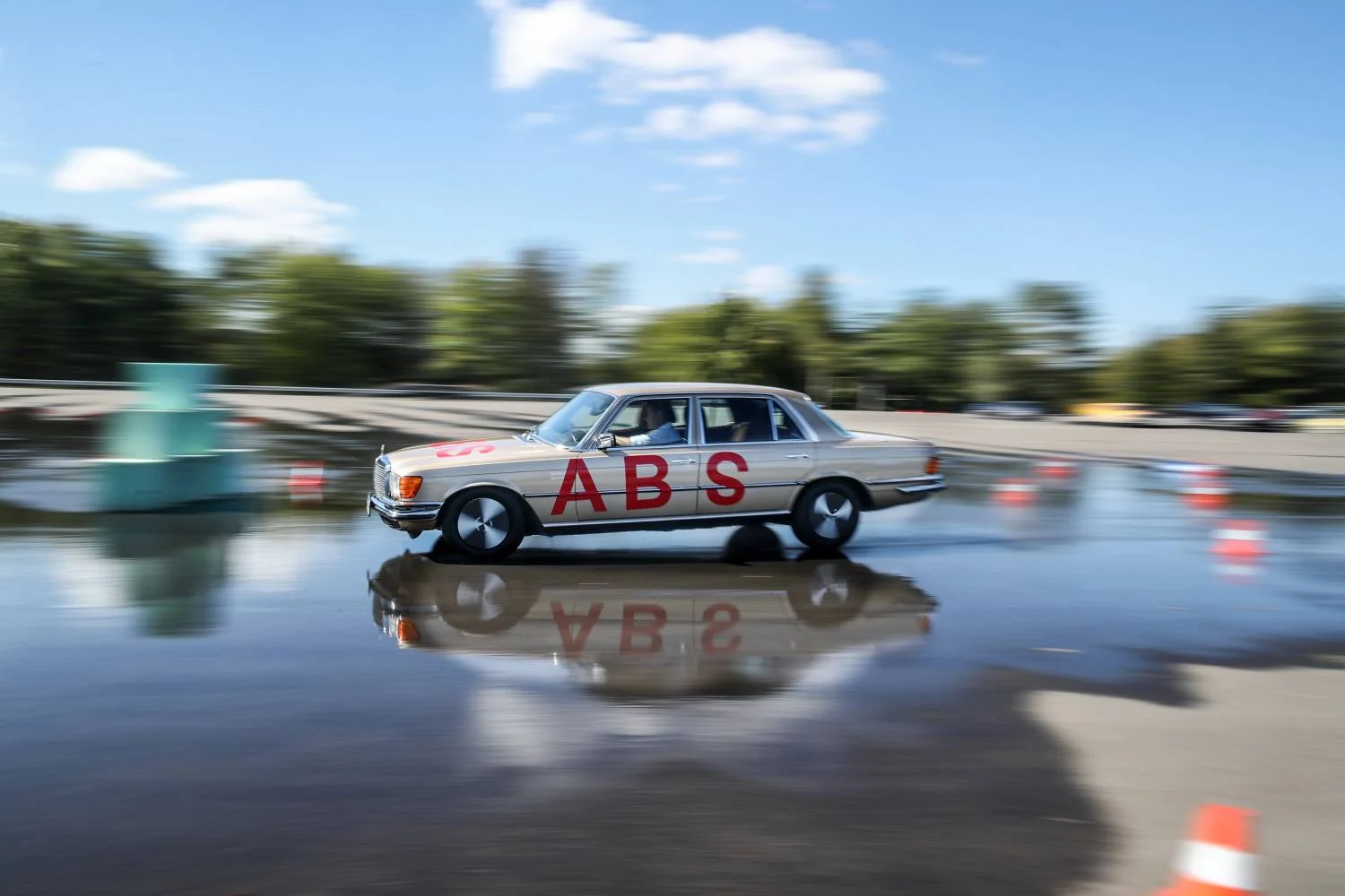 A silver Mercedes-Benz W116 S-Class marked ABS brakes on a wet test surface
