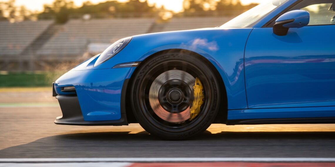 Porsche 911 GT3 braking on a race track, its yellow caliper clamping a grey carbon-ceramic disc