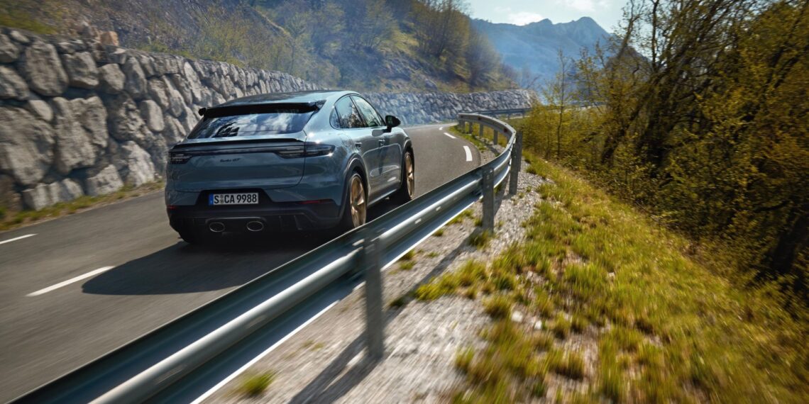 A grey Porsche Cayenne Turbo GT driving on a winding road beside a guardrail