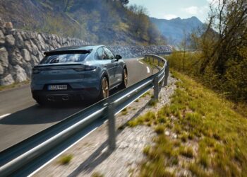 A grey Porsche Cayenne Turbo GT driving on a winding road beside a guardrail