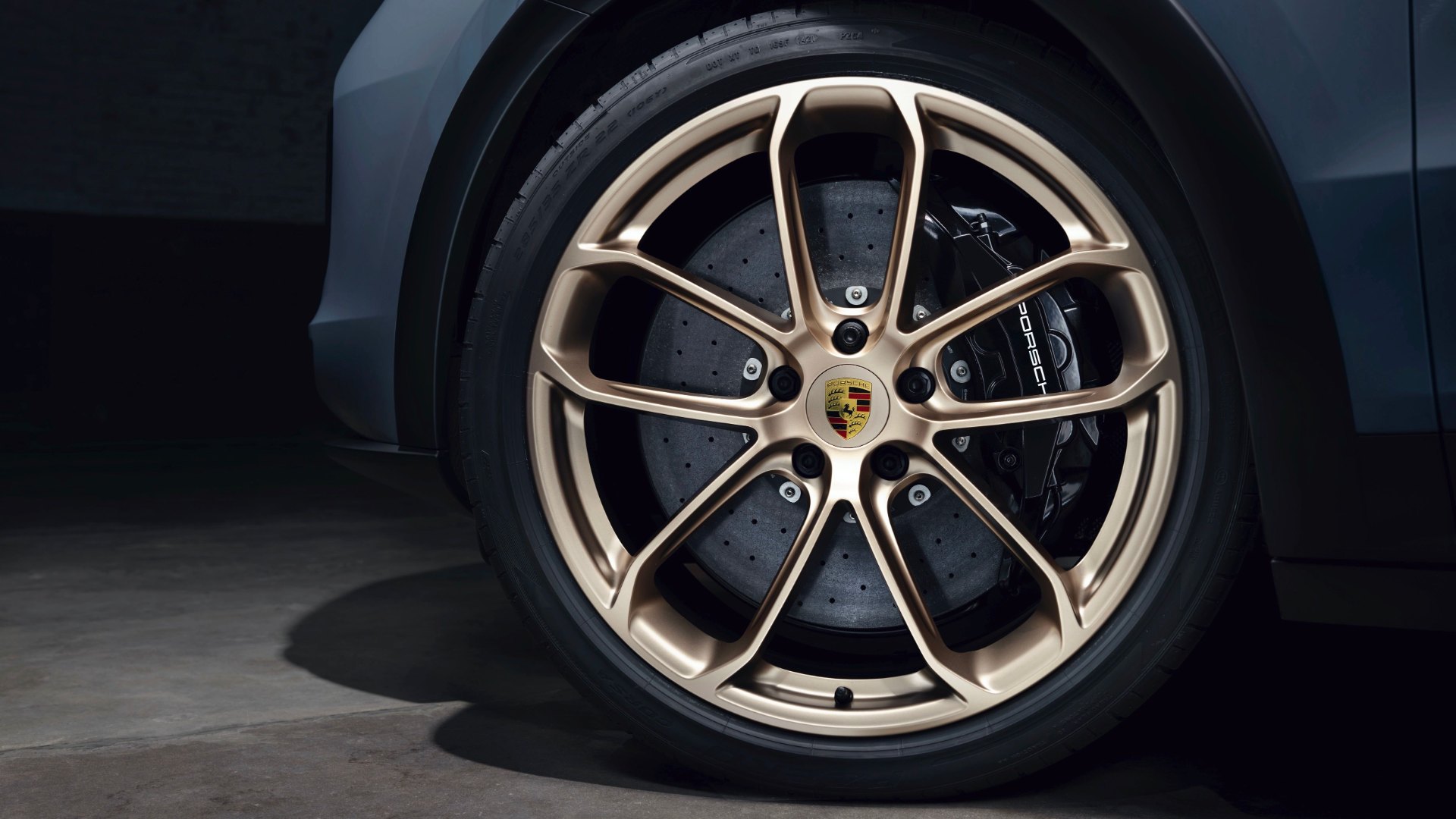 Close-up of a bronze-finished 22-inch Porsche Cayenne Turbo GT wheel in front of a cross-drilled ceramic brake disc and black caliper