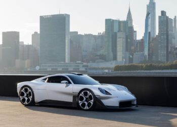 White Porsche Mission S vision model parked on a waterfront pier with the Manhattan skyline behind it