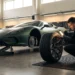 A technician inspects the sidewall of a removed performance tire beside an unbadged supercar in a workshop.