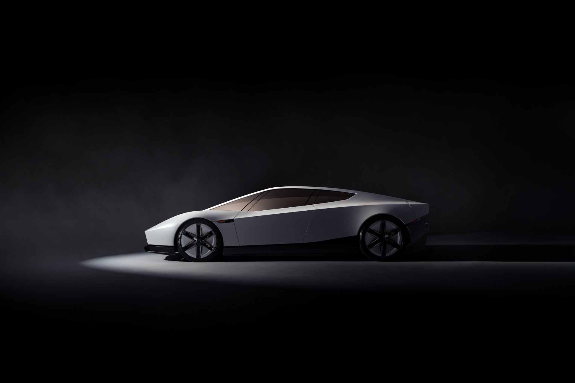 White second-generation Tesla Roadster in side profile under a studio spotlight