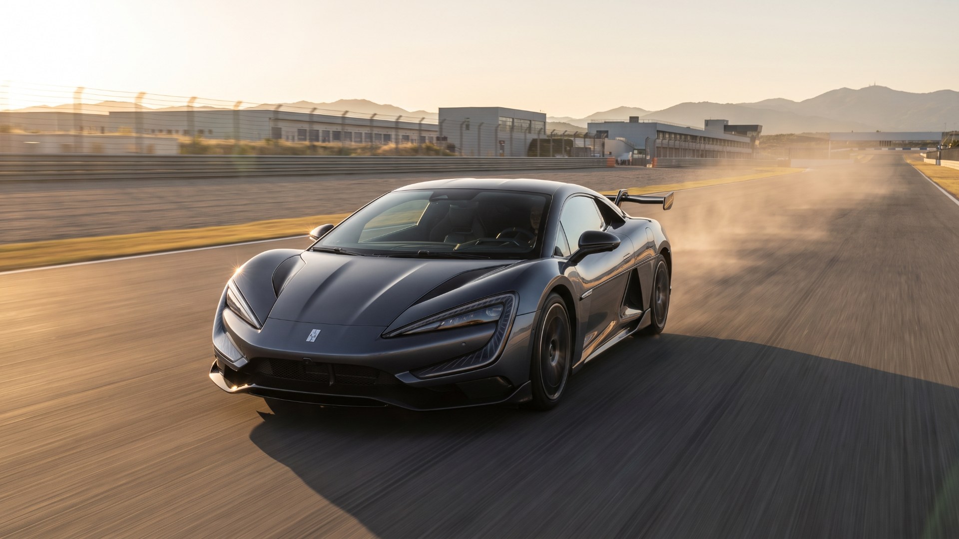 Dark grey Yangwang U9 electric supercar driving on a test track at sunset